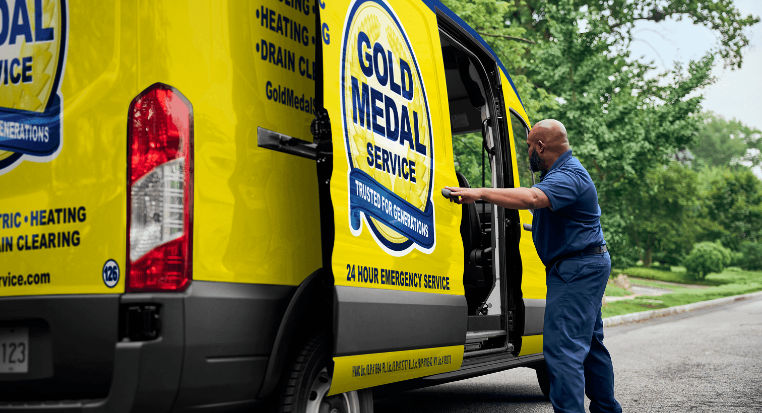 A professional Gold Medal technician opening a yellow service van on a residential street, ready to provide home HVAC, plumbing, and electrical services.